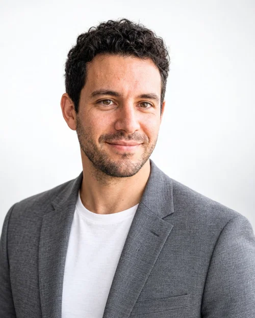 AI headshot in a grey blazer over a white t-shirt on a plain white background for a company website